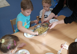 dzieci ze smakiem jedzą sałątkę warzywną